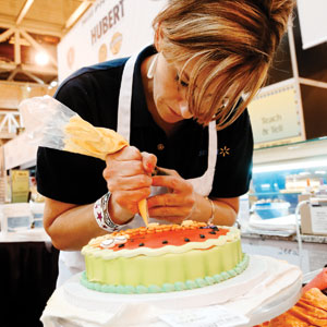 Third-place winner Stacie Clawson, Wal-Mart, decorates a cake on the show floor.