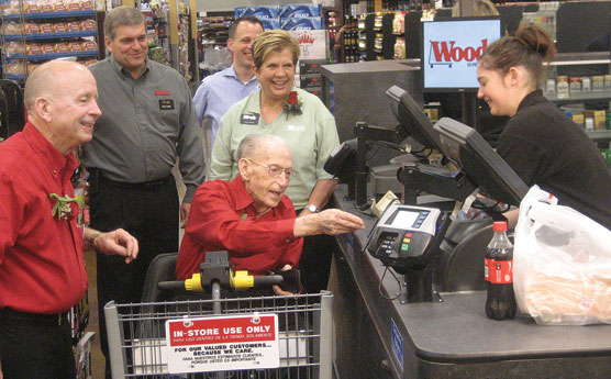 Don Woods Sr., 94, goes through the checkstand, flanked by (from left) his son, co-owner Don Woods Jr.; Craig Easter, chief executive officer; his grandson Jeff Woods; and co-owner Joan Woods.