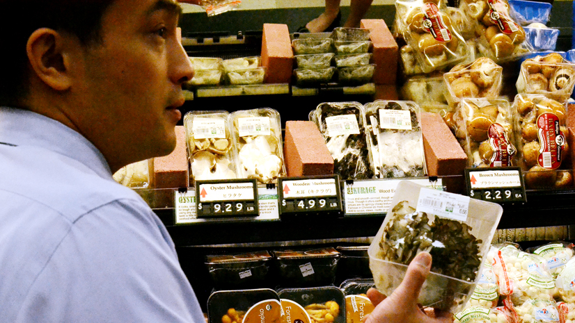 Store manager Takayuki Ono explains the different types of specialty mushrooms in Mitsuwa's produce department.